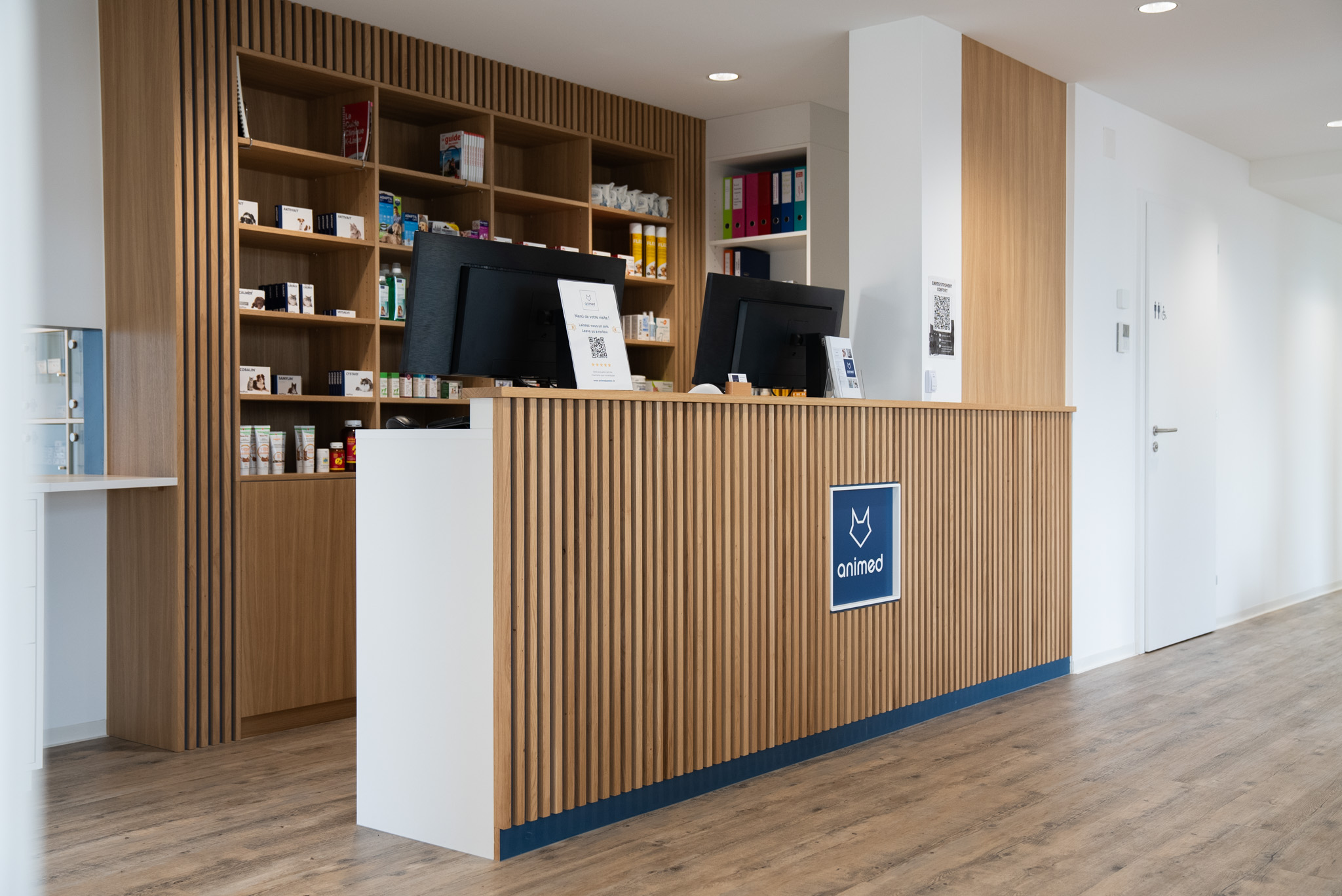 a counter with a computer and shelves in the background