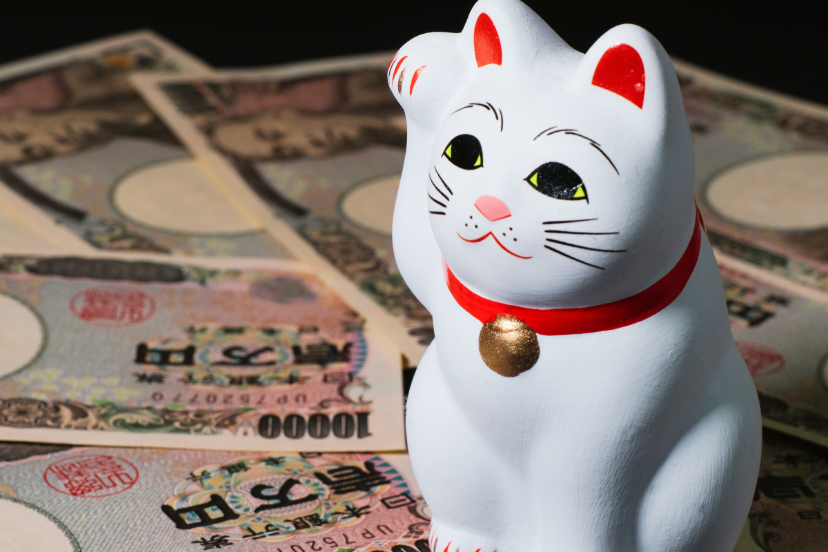 gros plan sur une figurine de chat blanc maneki neko assis sur des billets de banque japonais