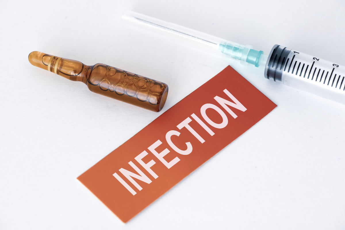 gros plan sur une fiole, une seringue et un panneau rouge indiquant INFECTION