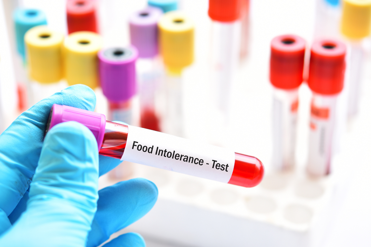 gros plan sur une main gantée qui tient une fiole où il est écrit Food Intolerance - Test