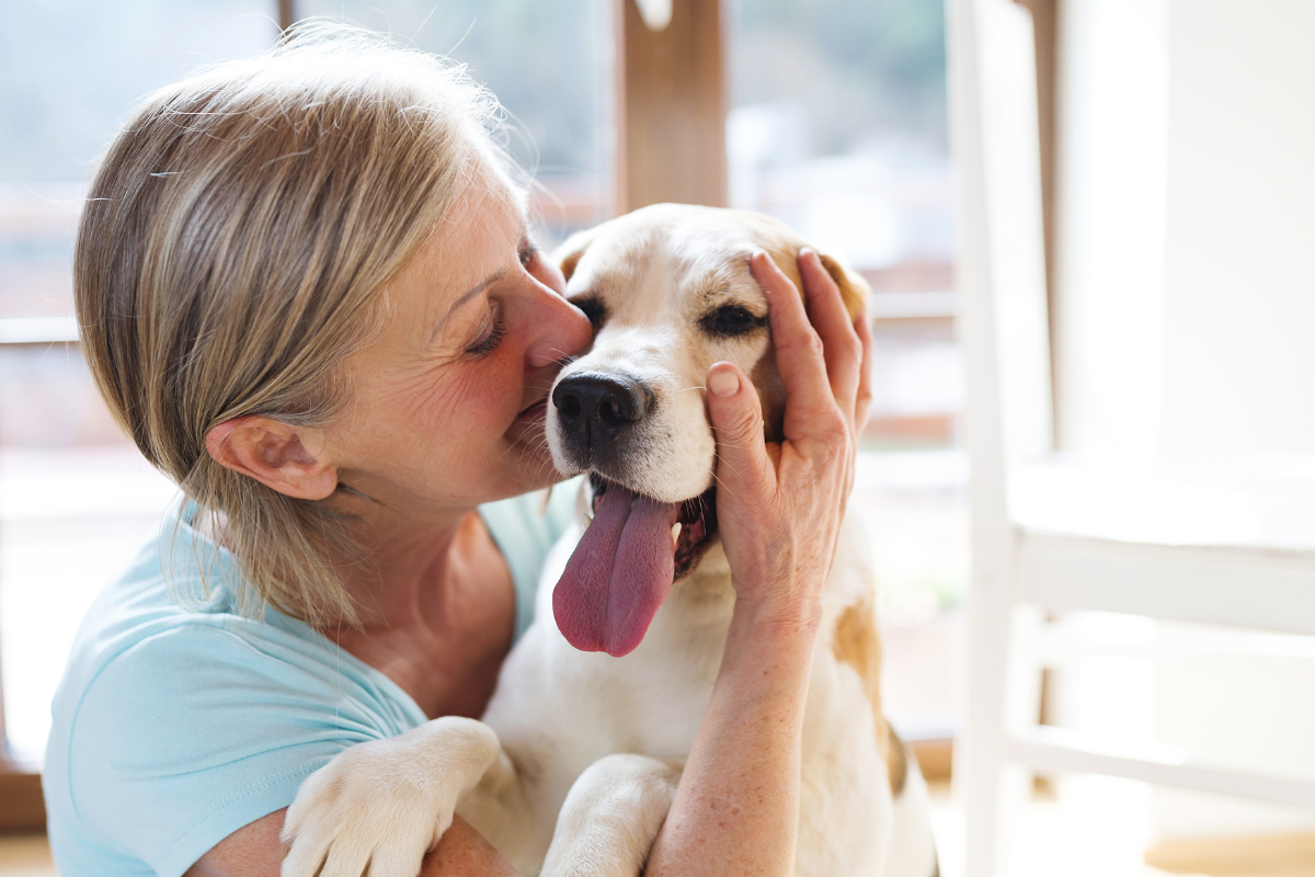 une dame embrasse son chien qui tire la langue